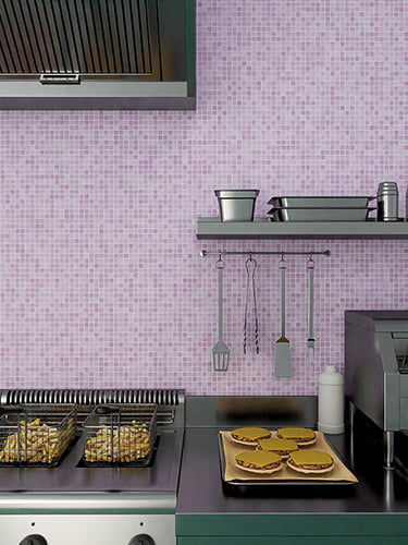 Professional kitchen setup with fryer baskets and burgers against a purple mosaic tile backsplash