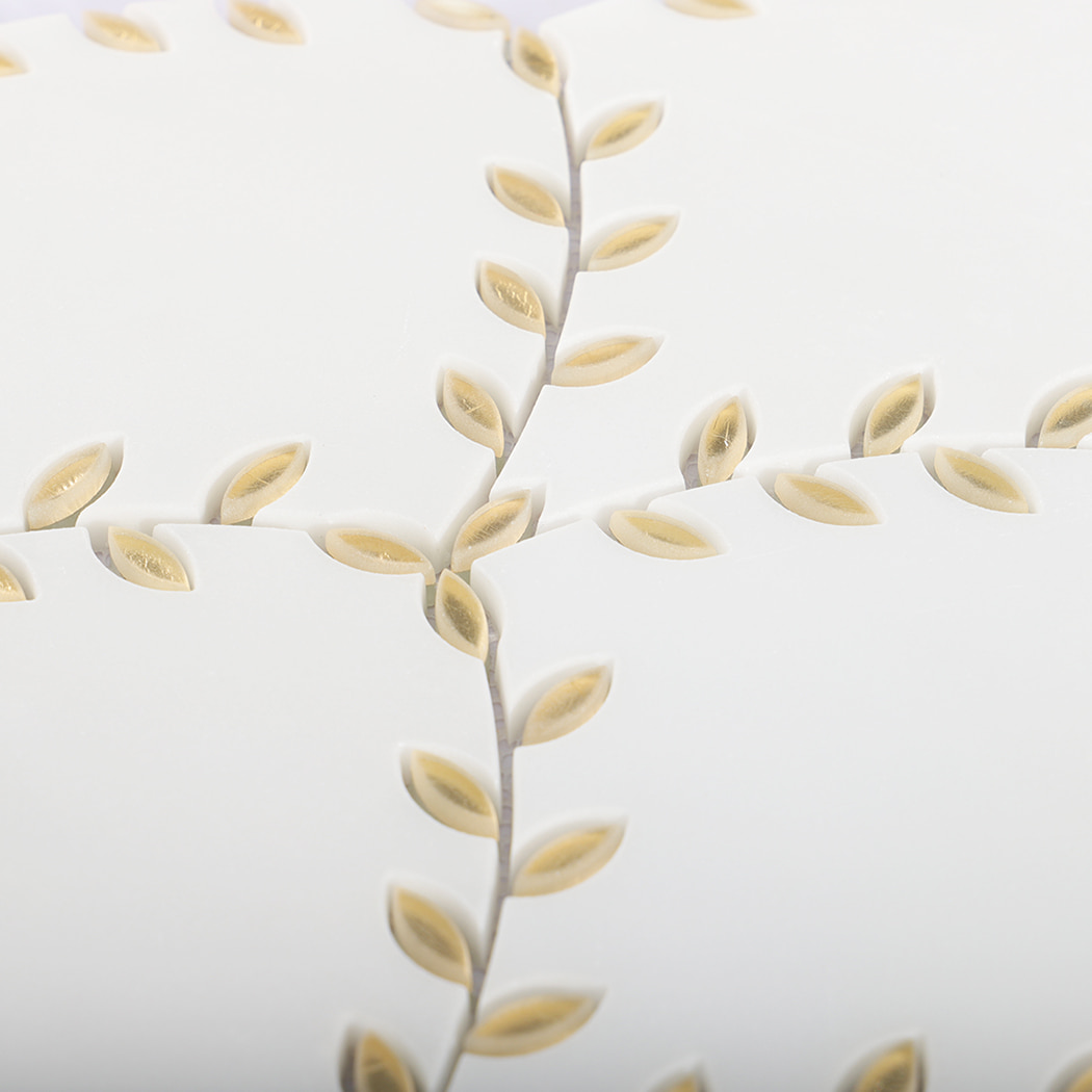 Detailed close-up of gold leaf patterns on a marble tile surface.