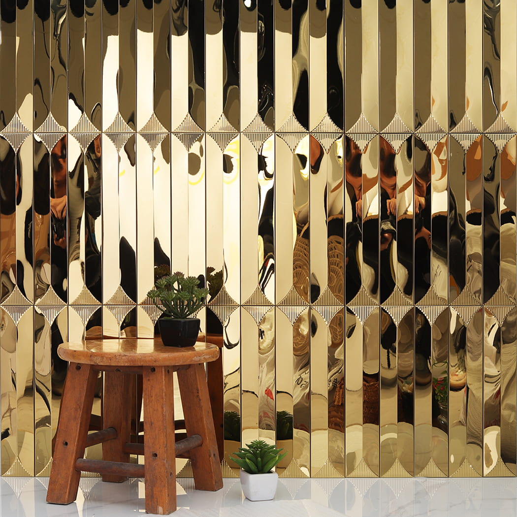 Gold 3D metal mosaic wall decor with a wooden stool and a small plant.