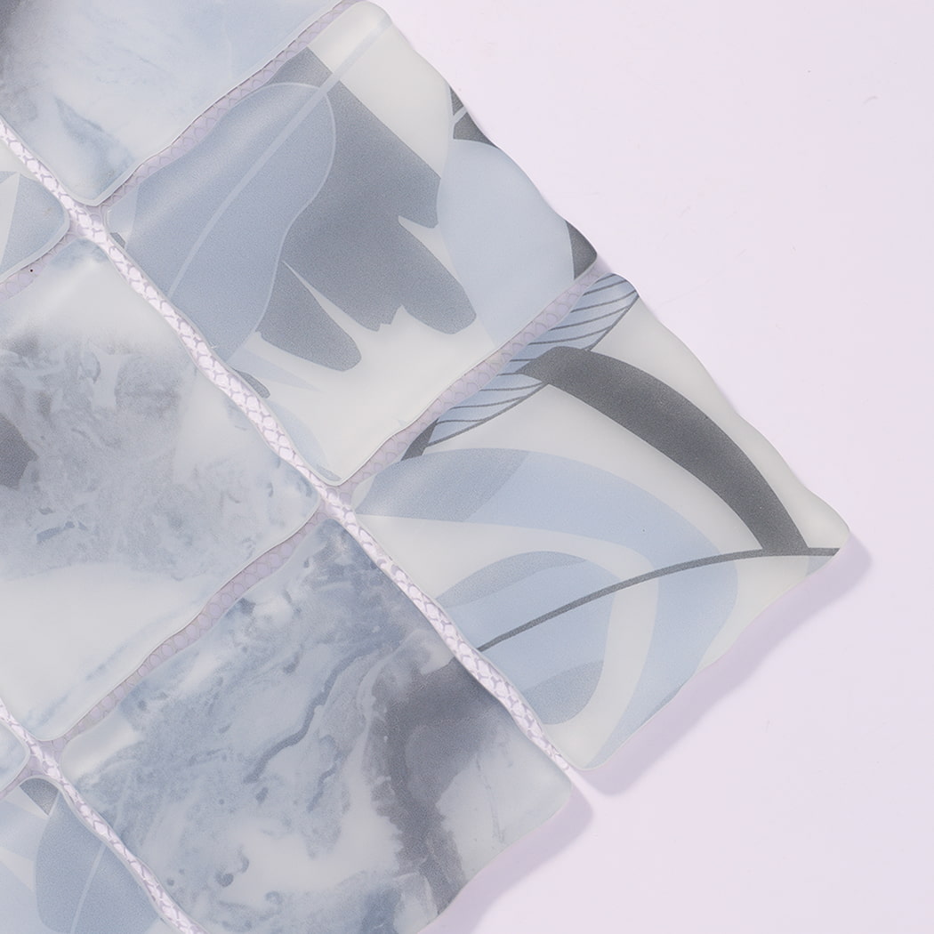 Close-up of light blue gray wavy glass mosaic tiles with botanical patterns