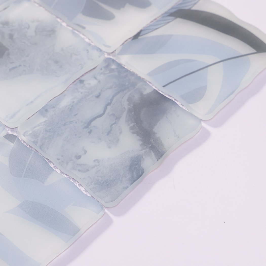 Edge detail of light blue gray wavy square glass mosaic tiles on mesh