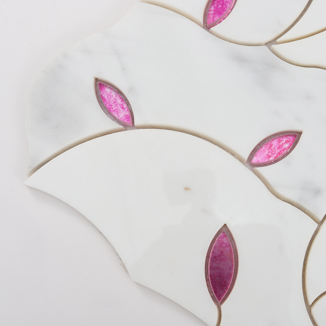 Close up of pink glass leaf inlay set into white marble mosaic tile