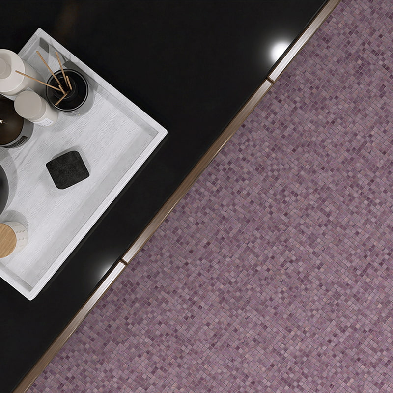 Overhead shot of black counter and purple water glass mosaic floor tiles with decorative tray