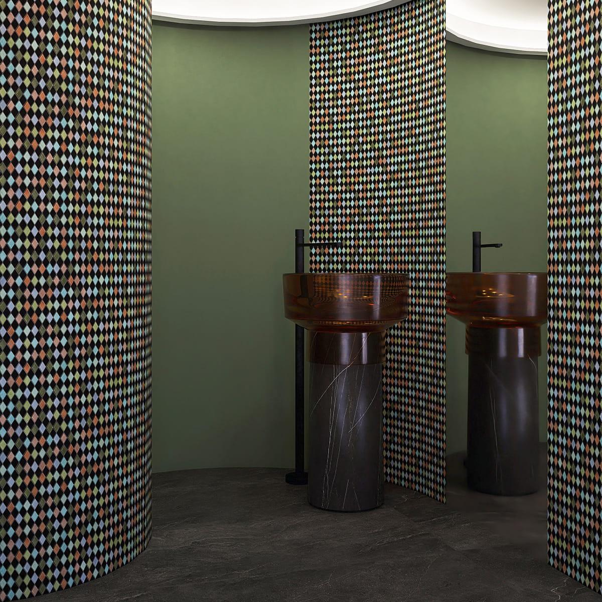 Modern bathroom with diamond-patterned mosaic tile walls and a sleek black pedestal sink.