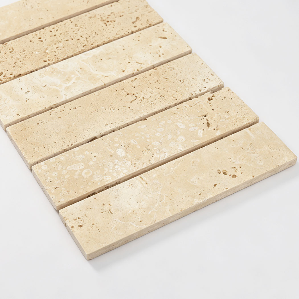 Angled close-up of beige travertine strip mosaic showing natural pores and veining