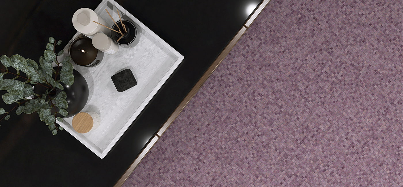 Tray with eucalyptus sprig on black surface next to purple water glass mosaic floor tiles