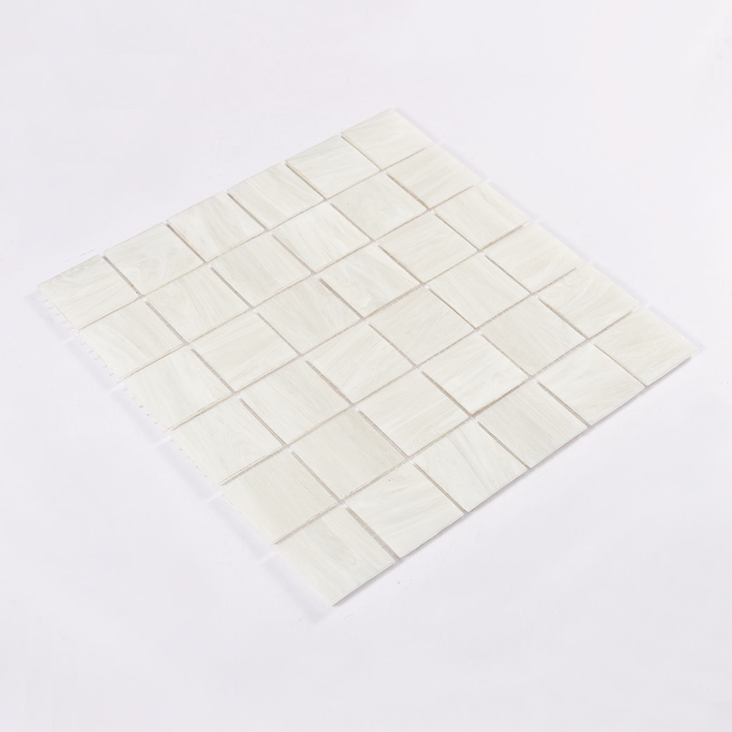 Angled perspective of pearl white square glass mosaic sheet laid flat
