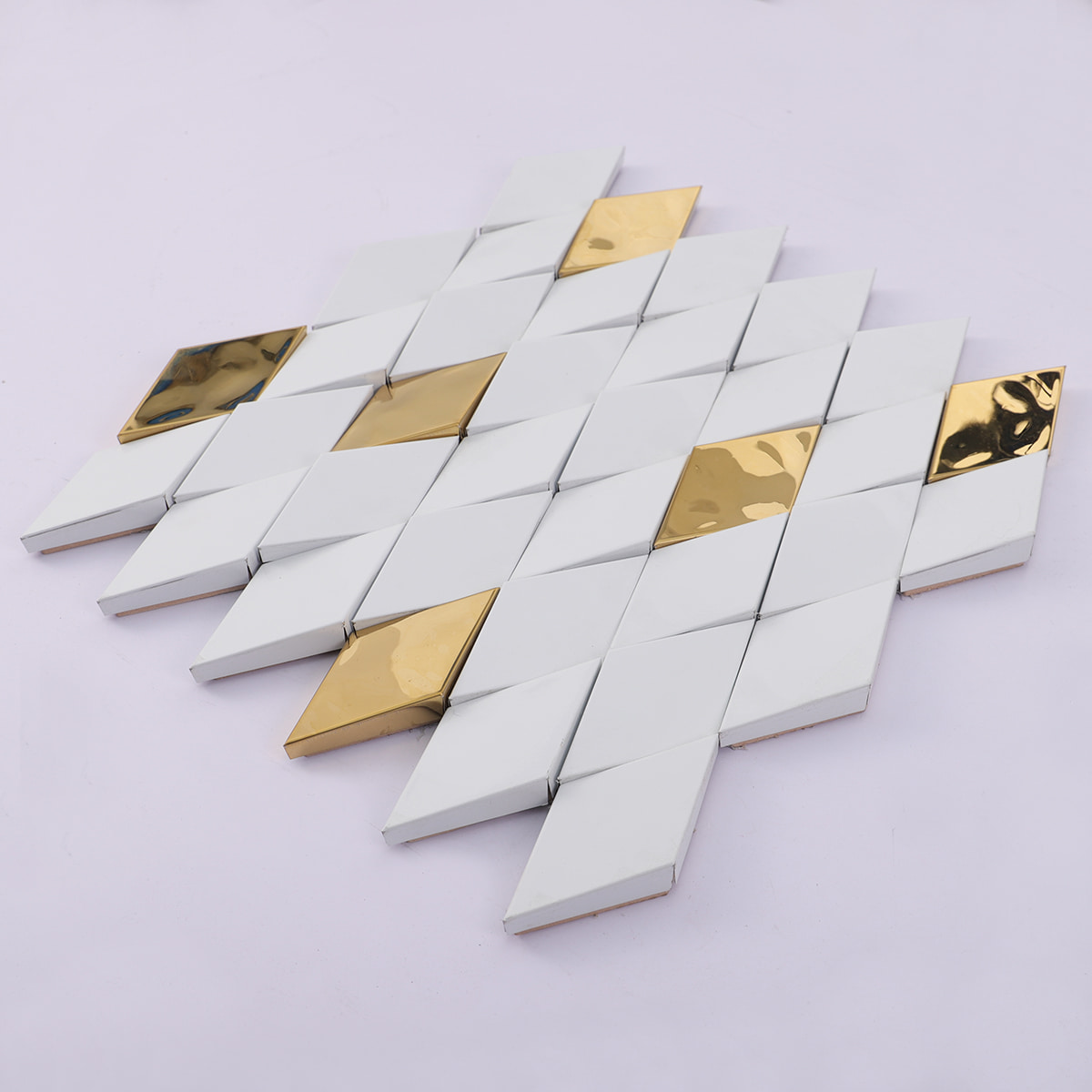 Perspective angled photograph of a 3D white and gold diamond mosaic tile sheet.