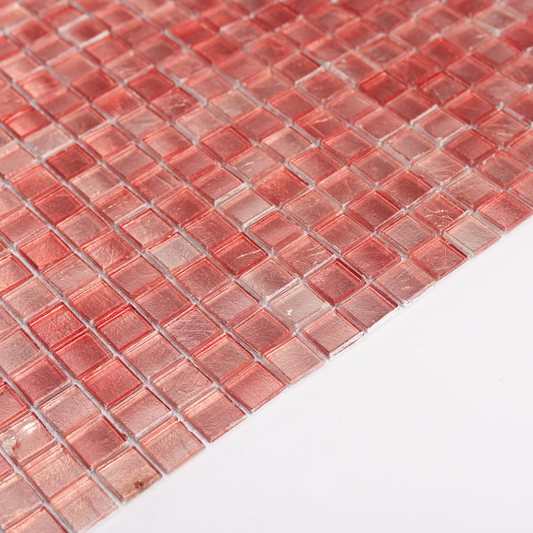Angled perspective of pink glass mosaic tile sheet showing thickness and shine