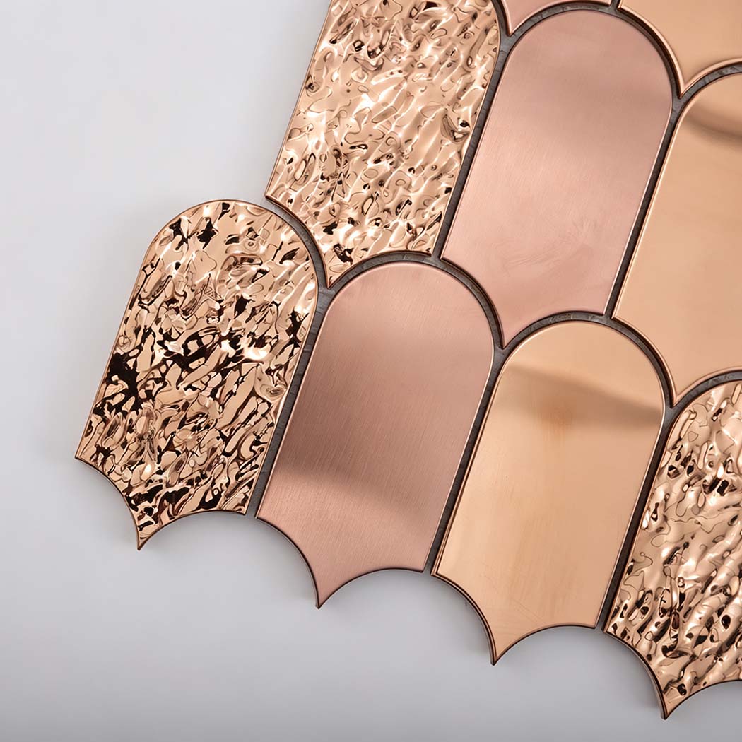 Close-up of brushed mirror and textured rose gold scallop mosaic tiles