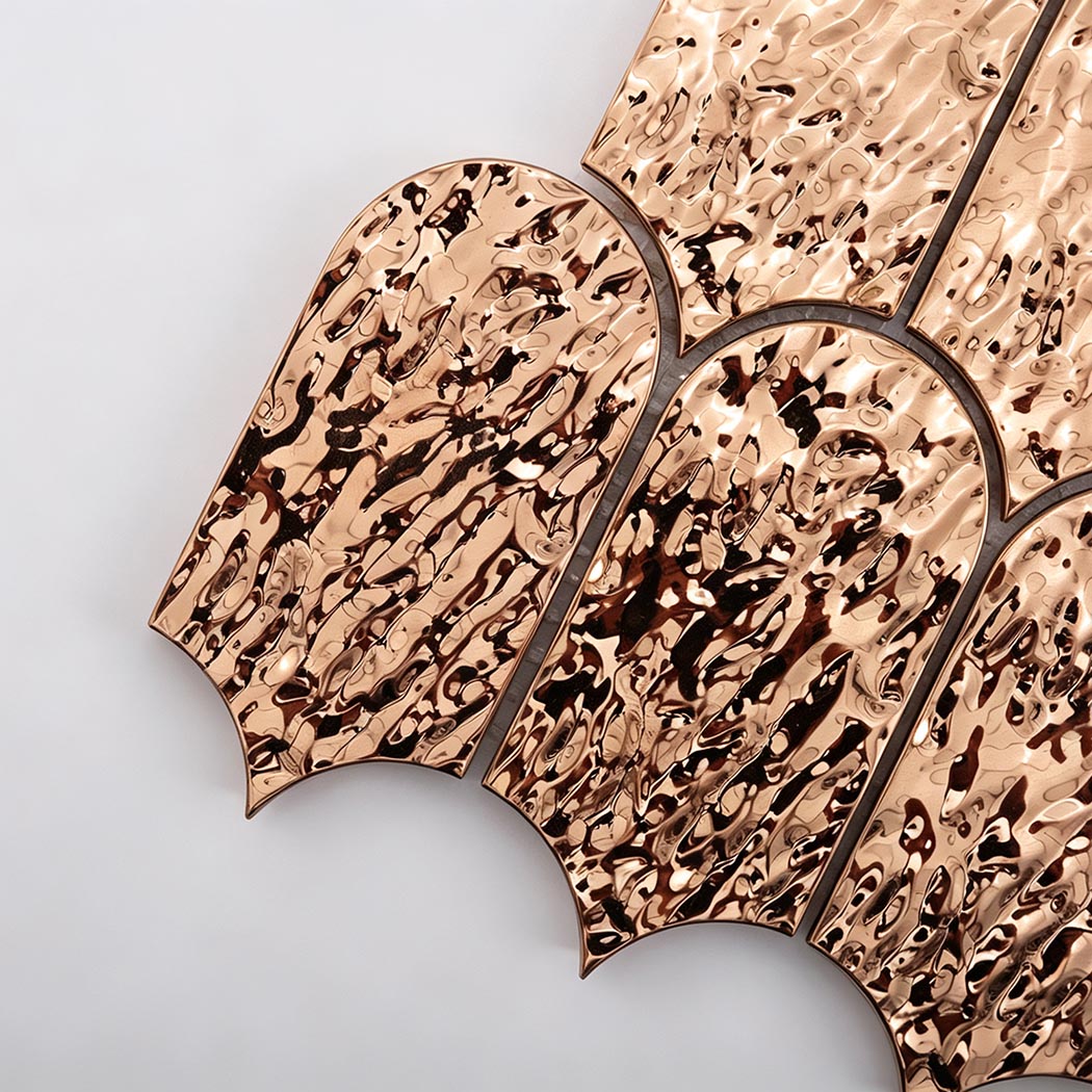 Close-up of reflective rose gold hammered scallop metal mosaic tile texture