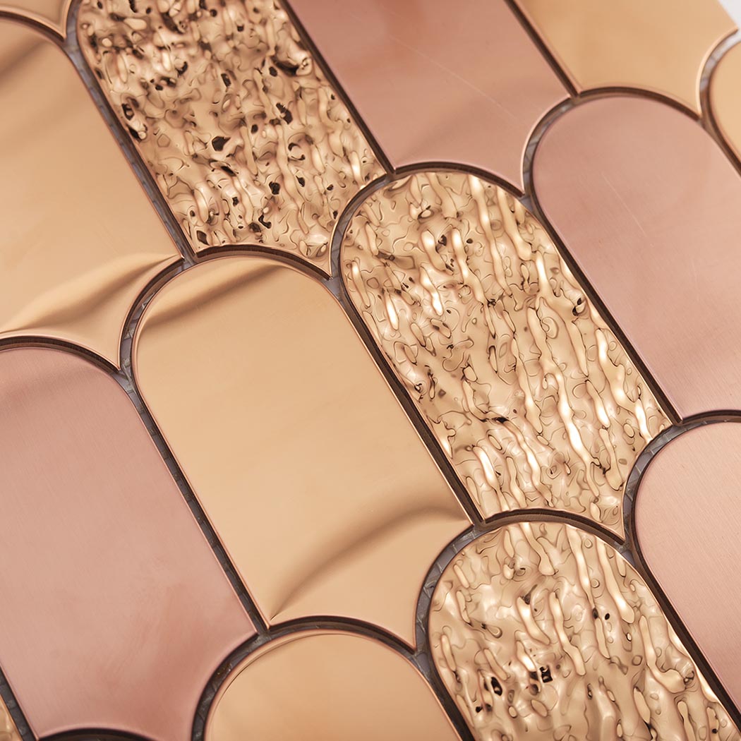 Detailed view of rose gold brushed mirror and textured scallop metal tiles