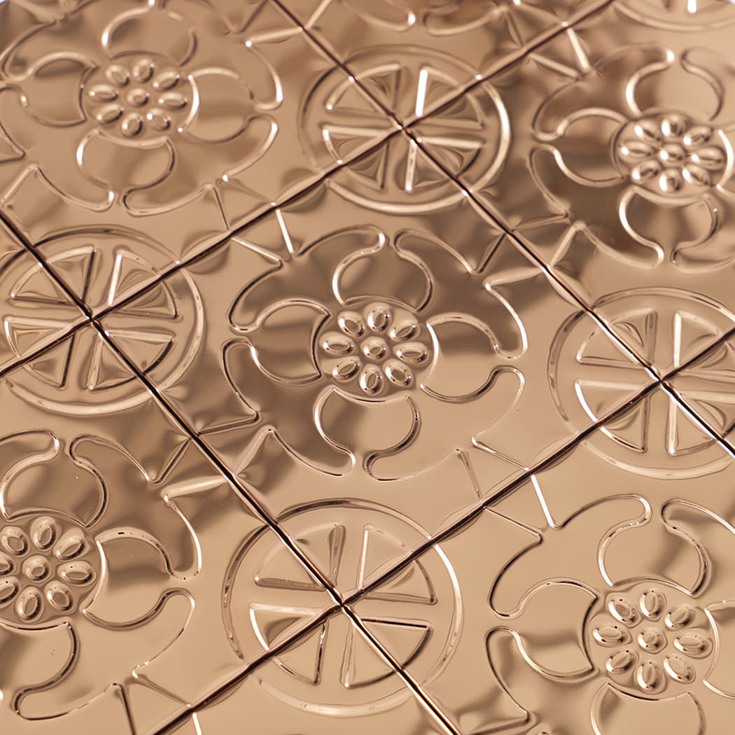 Macro texture of rose gold embossed tiles showing raised petals and glossy reflections
