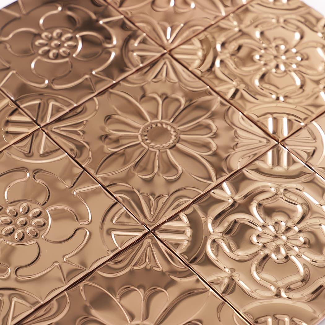 Detailed close up of rose gold embossed metal tile sheet with raised flower motifs