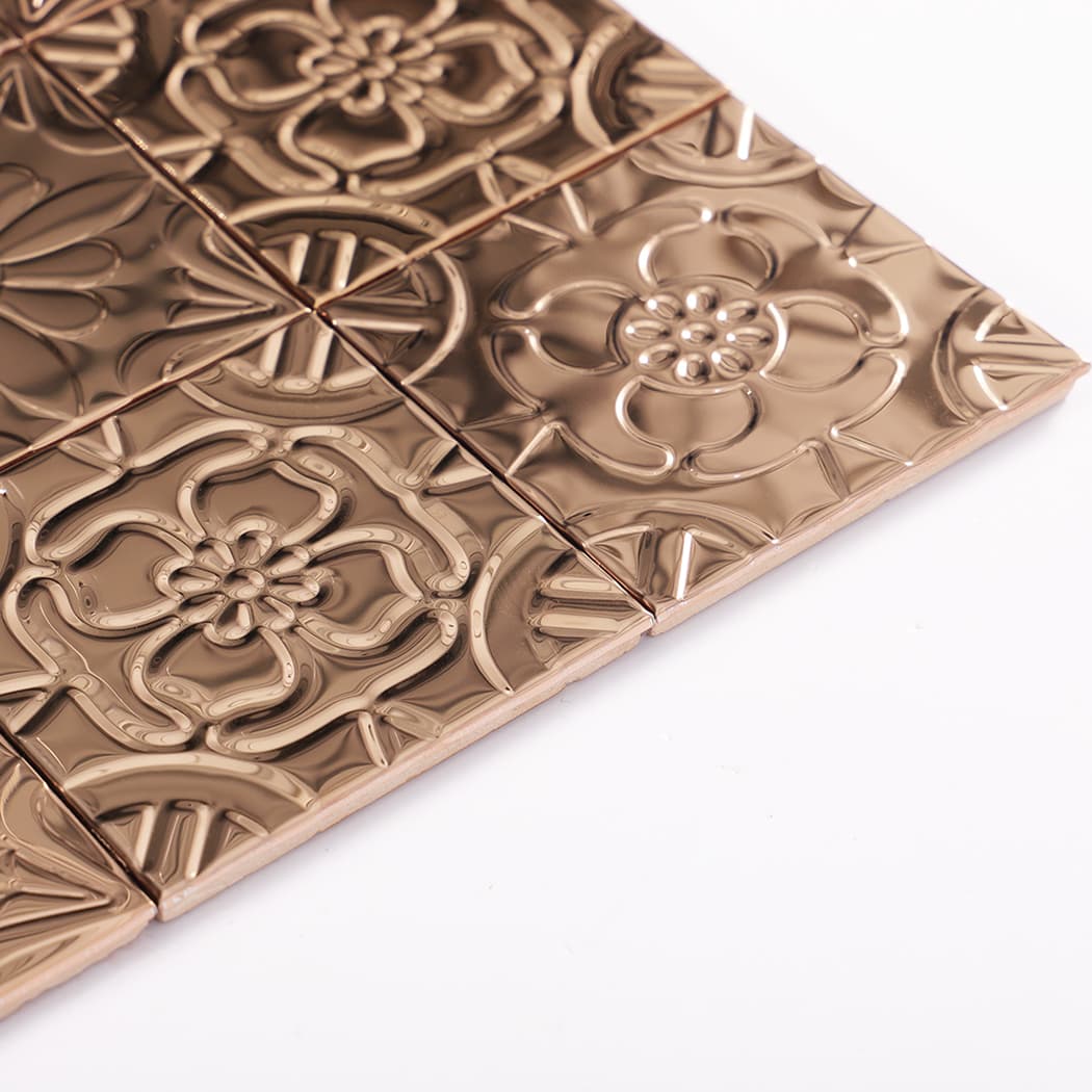 Angled edge view of rose gold embossed metal tile sheet showing thickness and glossy finish