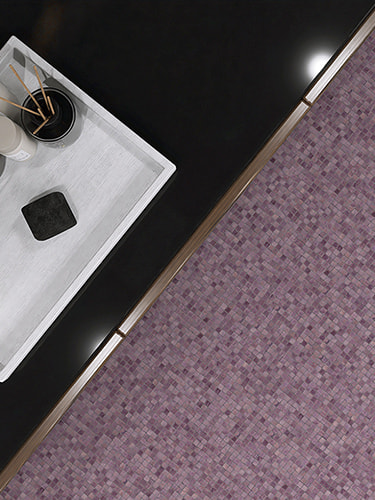 Tray with candle and diffuser on black surface next to purple water glass mosaic floor tiles