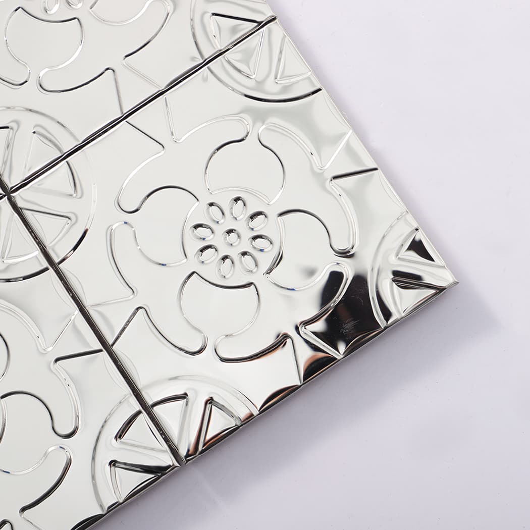 Close up of silver embossed flower mosaic tile corner showing glossy texture and seams.