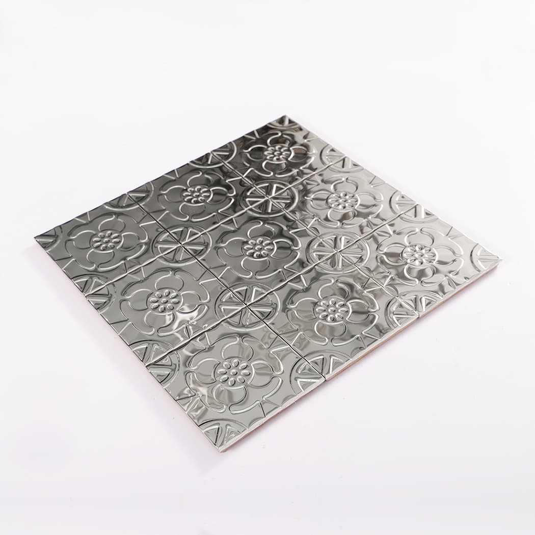 Perspective view of silver embossed flower mosaic tile sheet on a white background.
