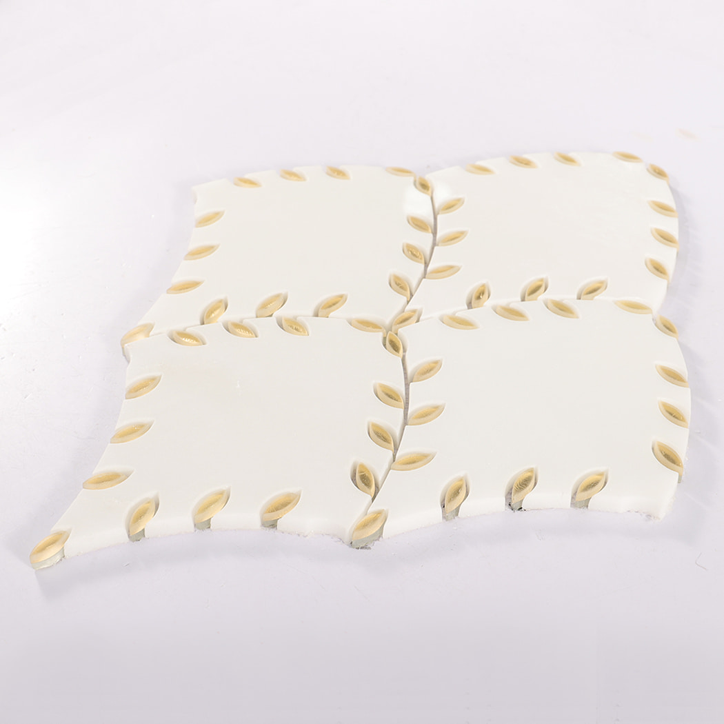 Angled view of a marble tile featuring a gold leaf border design.