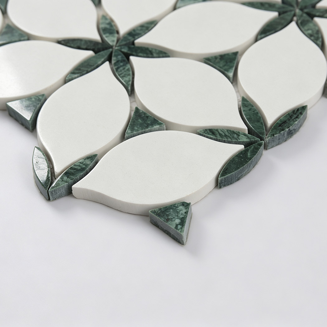 Angled view of white leaf and green marble mosaic tile surface