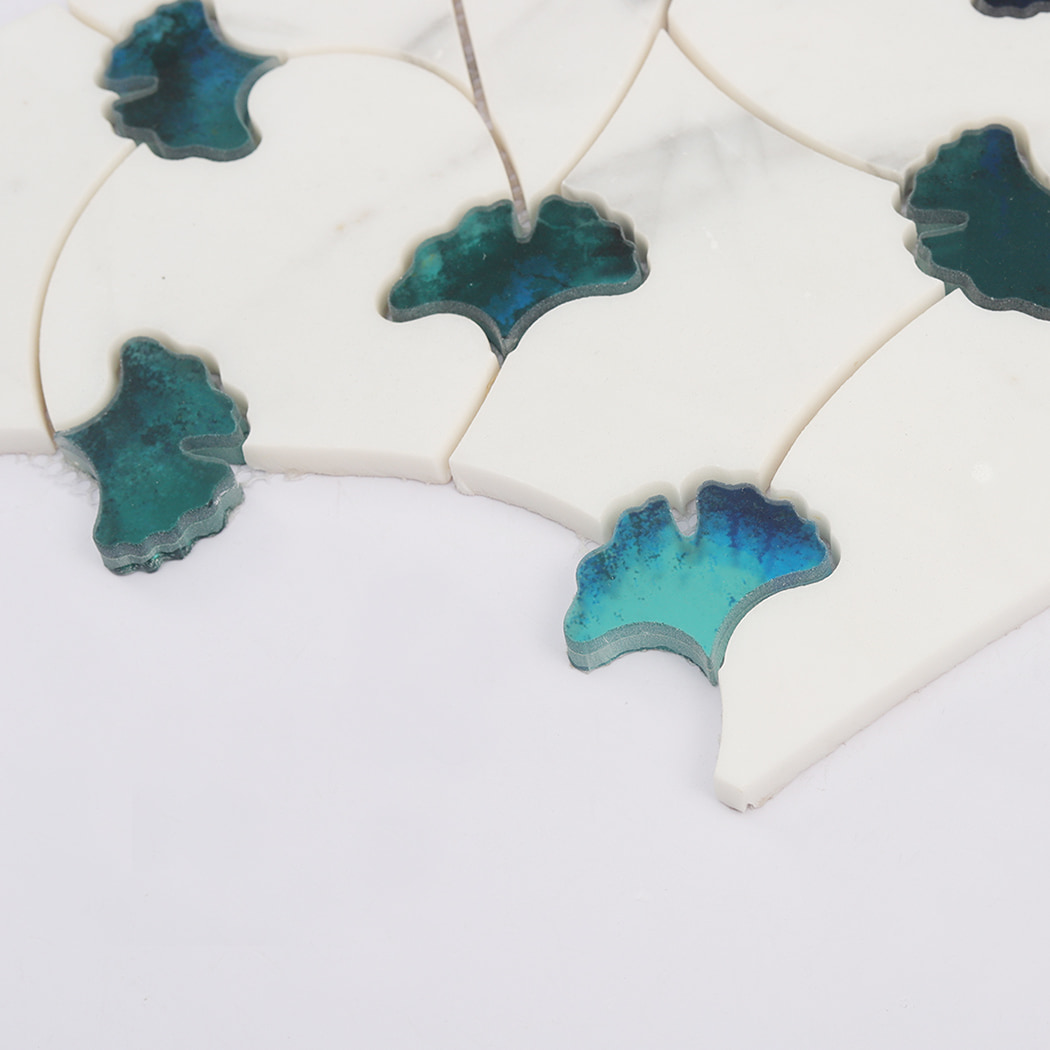 Angled view showing depth of white marble and teal glass waterjet floral mosaic