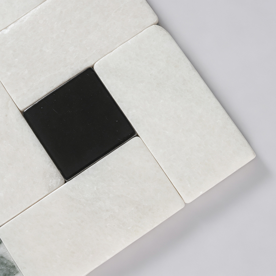 Close-up of white marble rectangles arranged around a black square tile