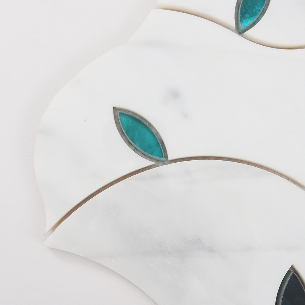 Close up detail of teal glass leaf inlay set into white marble mosaic tile
