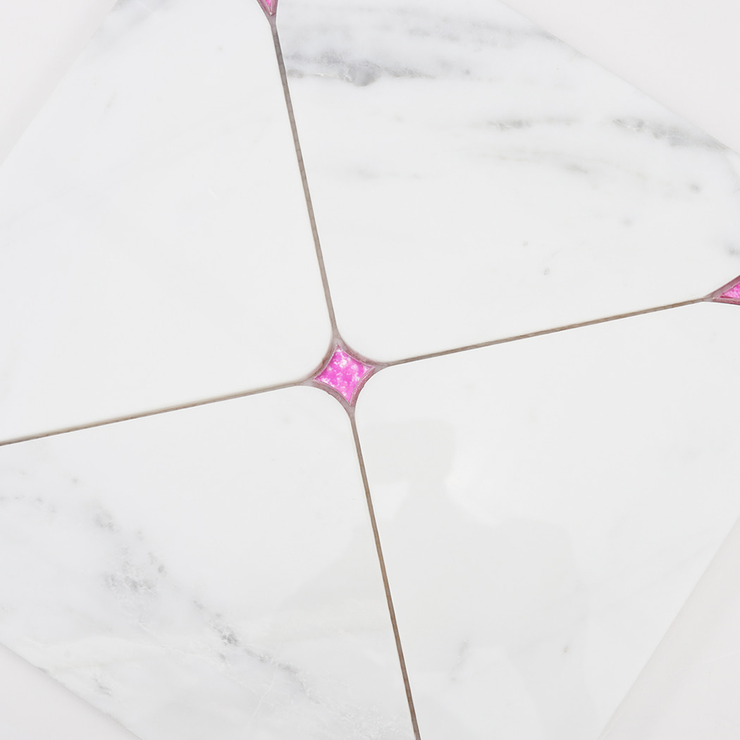 Detailed view of pink glass center joint connecting white marble mosaic pieces
