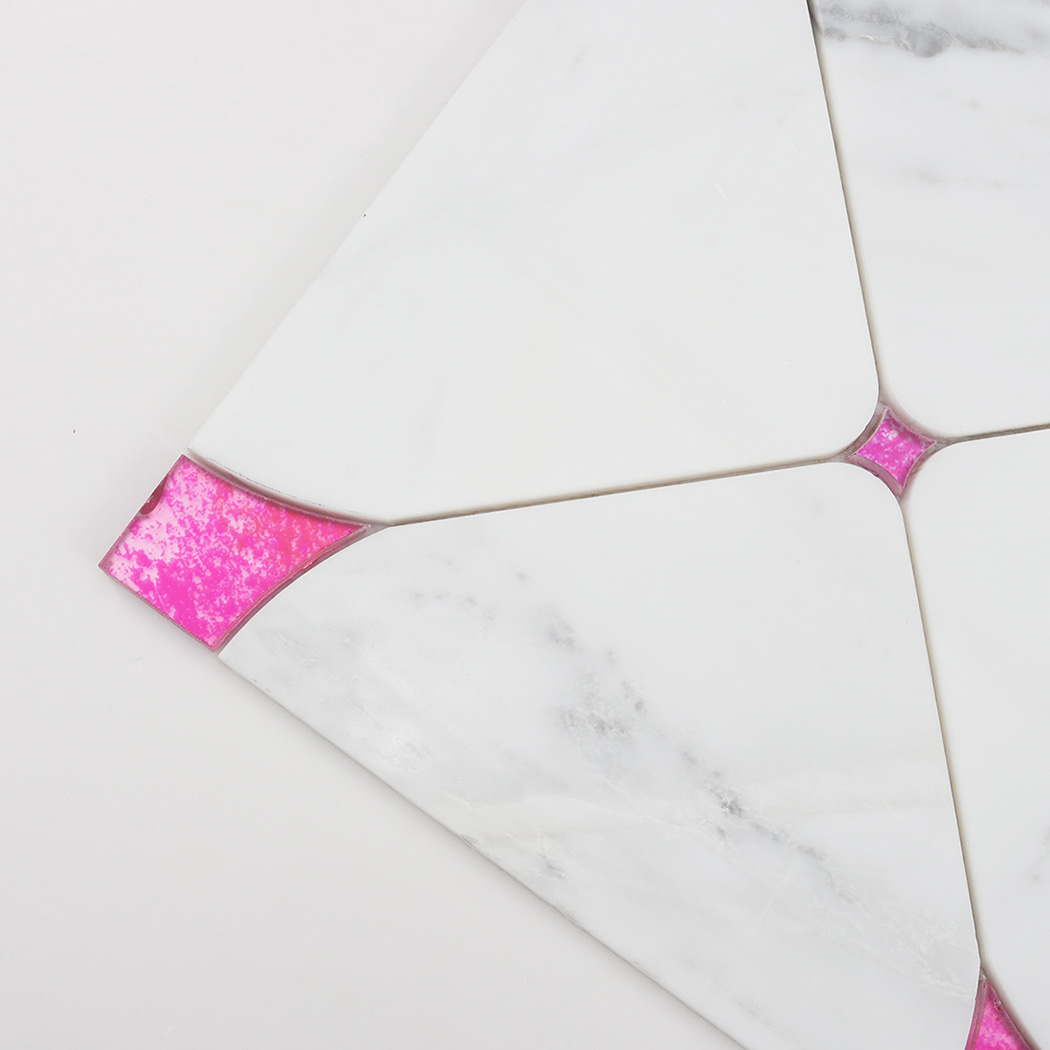 Close up of pink glass corner accent set into white marble mosaic tile