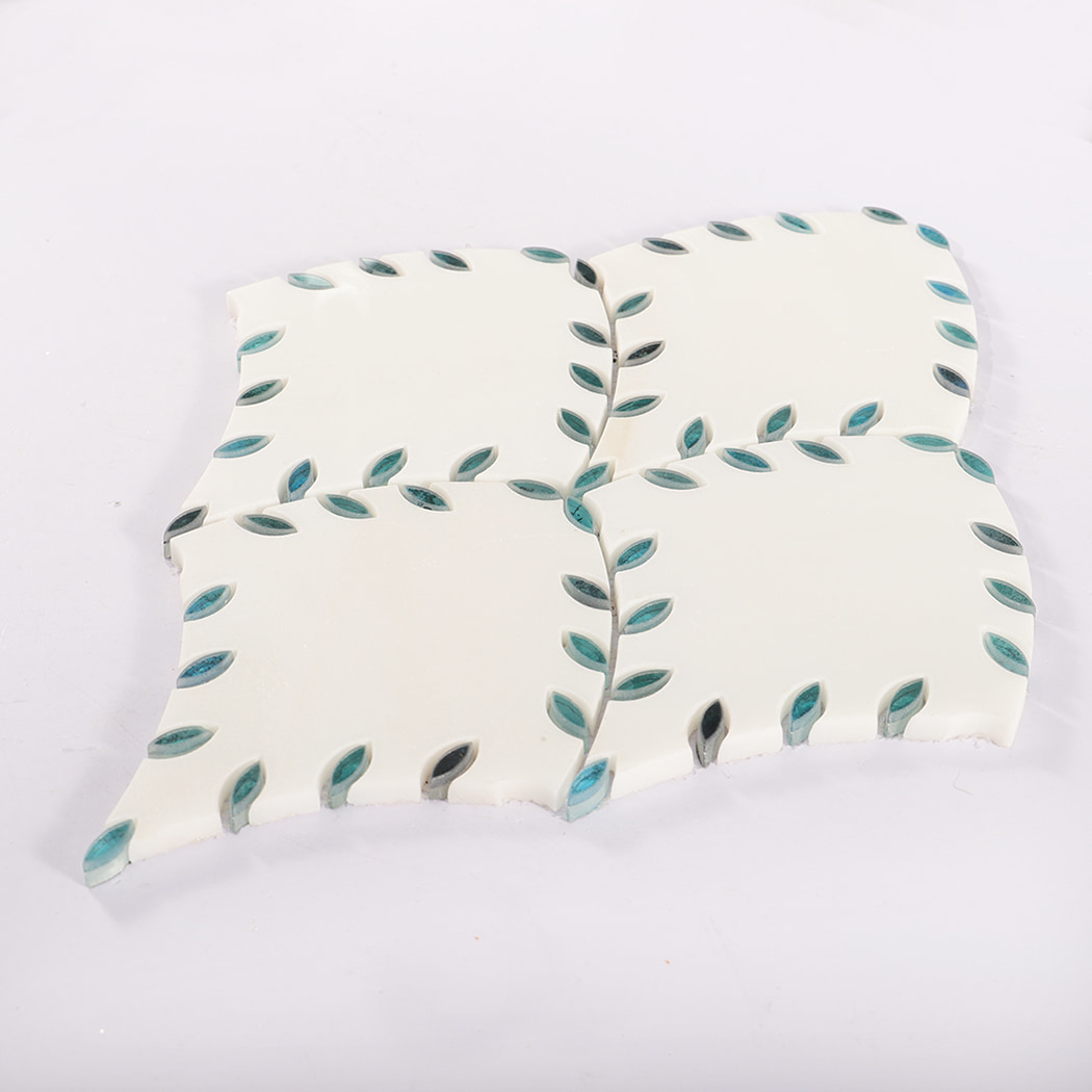 Angled view of white marble mosaic tile decorated with blue leaf accents.