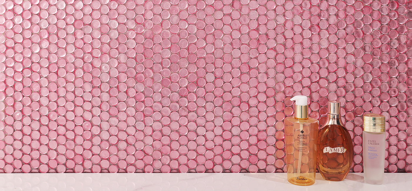 Panoramic view of pink penny glass mosaic backsplash behind bottles