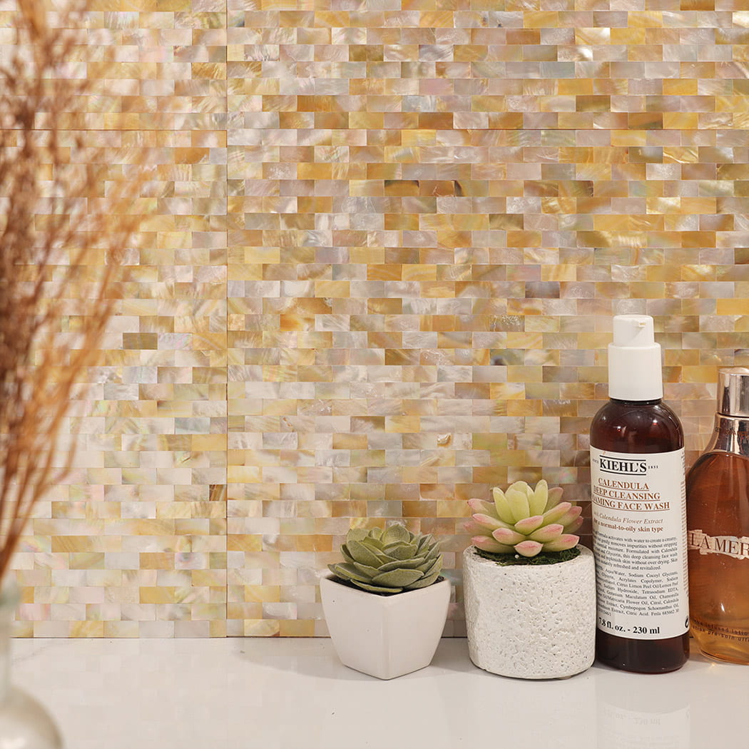 Yellow mother of pearl shell mosaic wall with plants and skincare bottles.