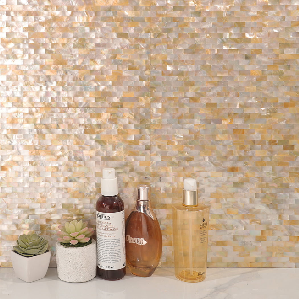 Yellow mother of pearl shell mosaic wall with skincare bottles and plants.