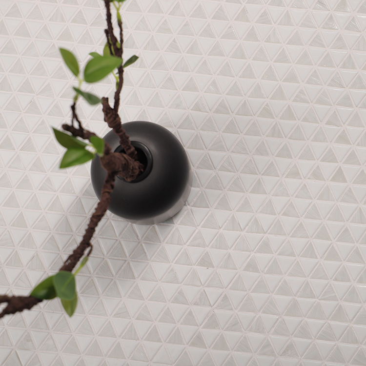 Triangle white mosaic tiles in a checkboard pattern on the floor with a plant on top.