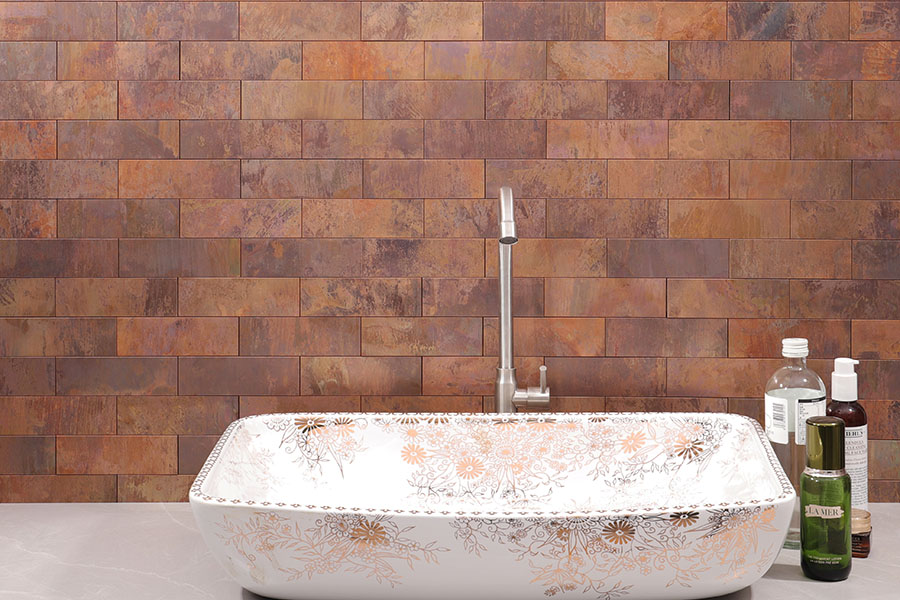 Aged copper subway tile wall with warm metallic texture behind a sink