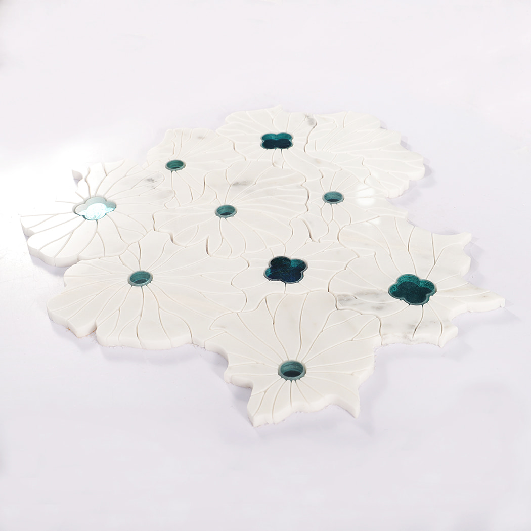 Angled view of flower-shaped marble mosaic tile sheet with blue glass accents.