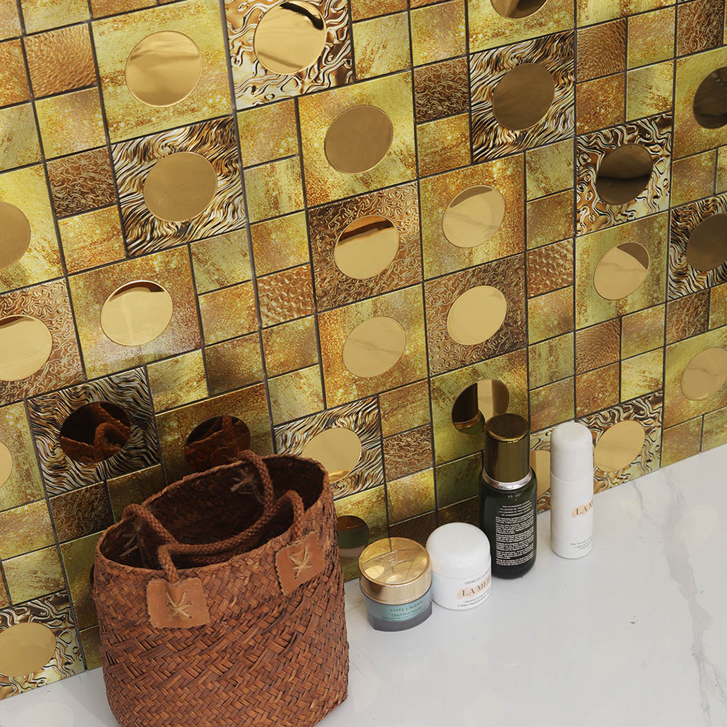 An angled view of a gold mosaic backsplash wall behind vanity counter products.