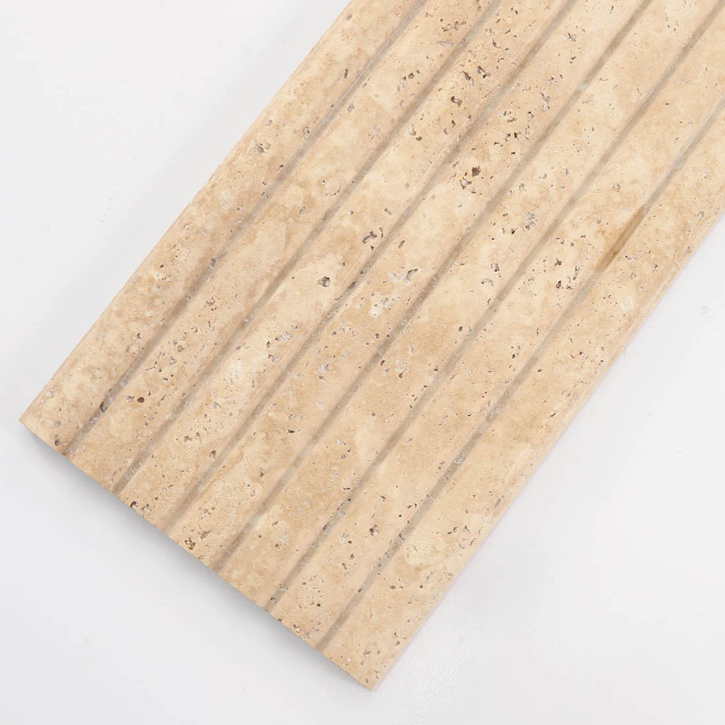 Slanted view of a fluted beige travertine tile showing its ribbed texture and pits.