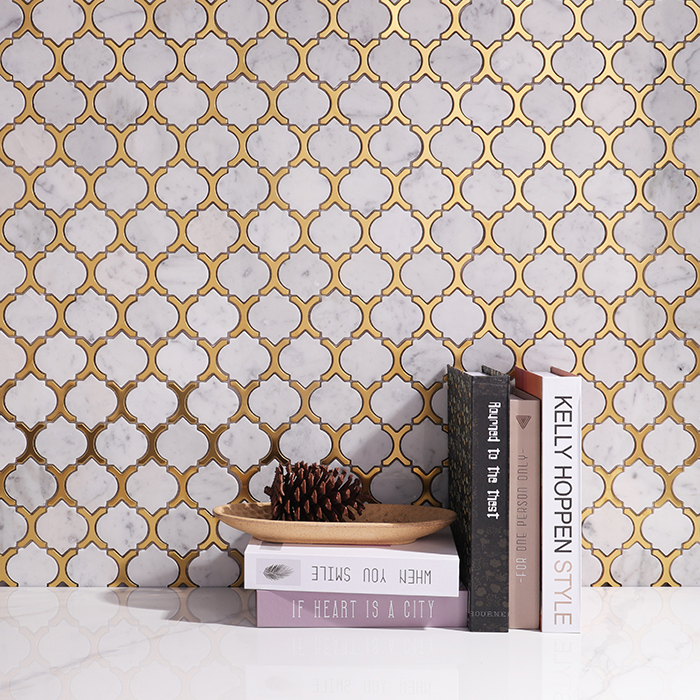 Arabesque white marble and gold metal mosaic tiles on wall with books in the foreground