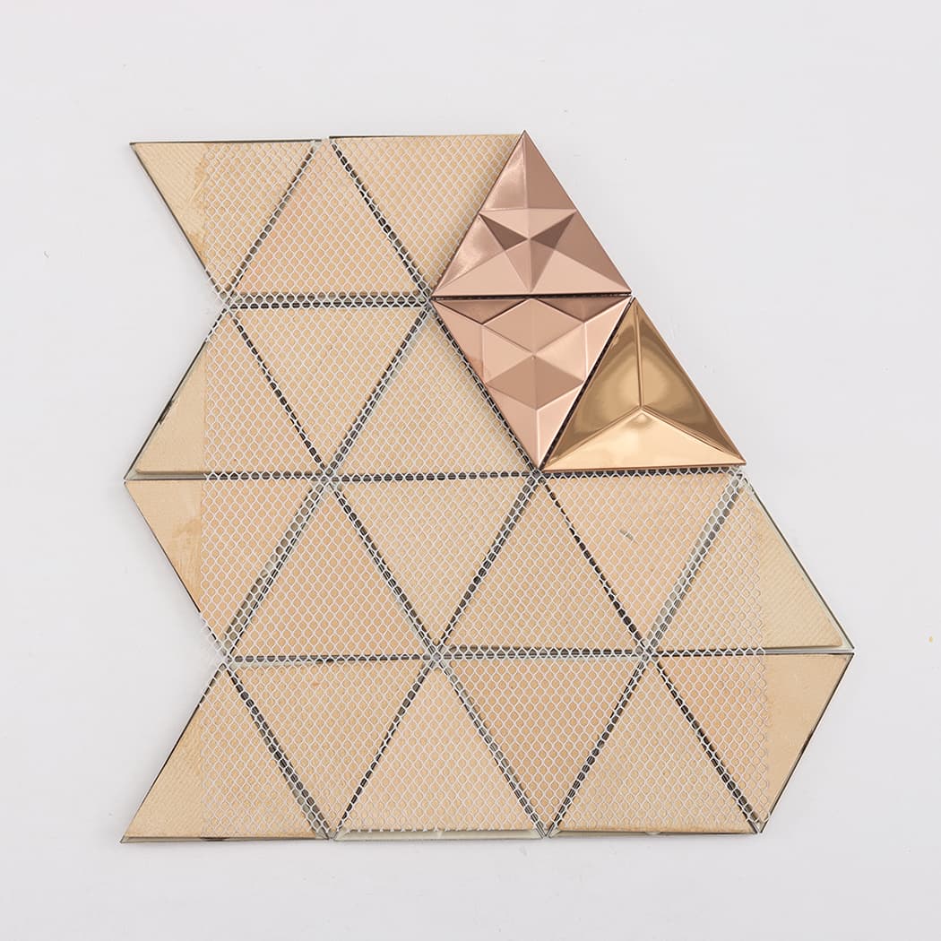 The reverse side of a rose gold tile sheet showing the white mesh adhesive backing.