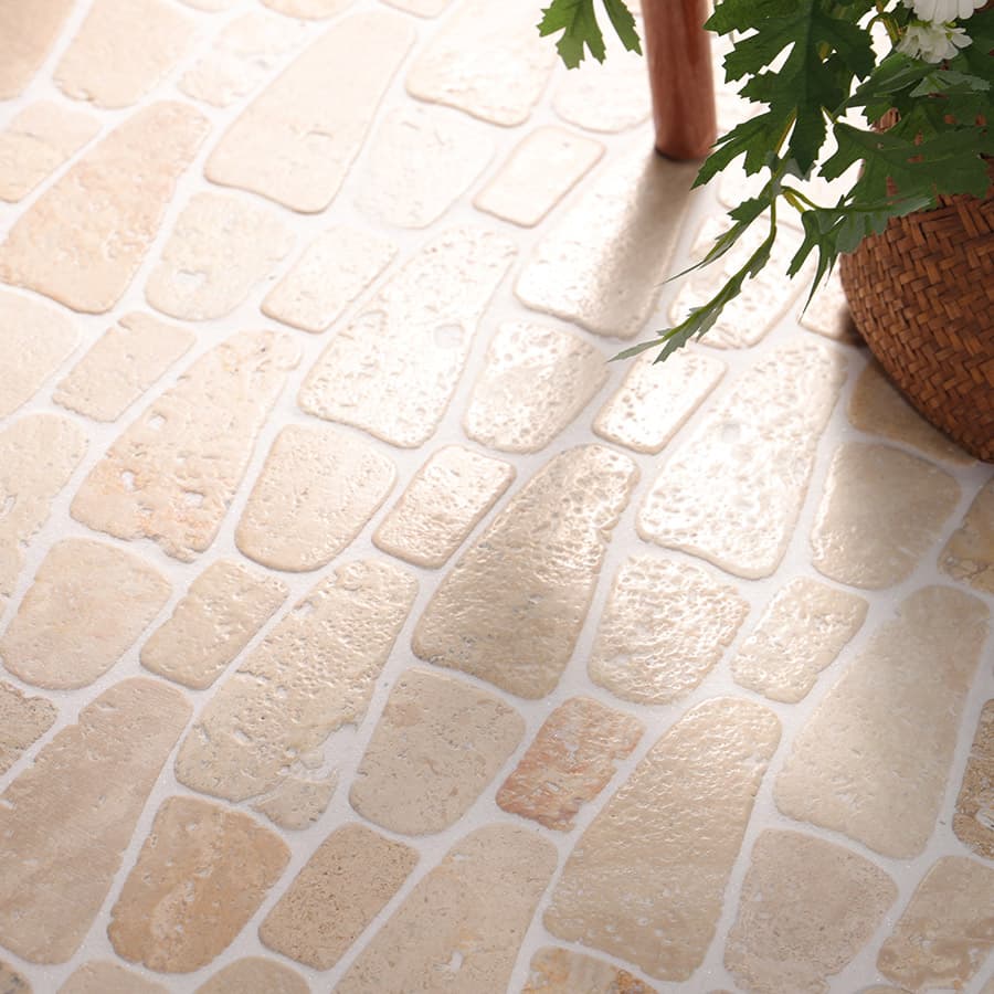 Outdoor travertine tiles with natural beige stone texture and woven basket plant decor.
