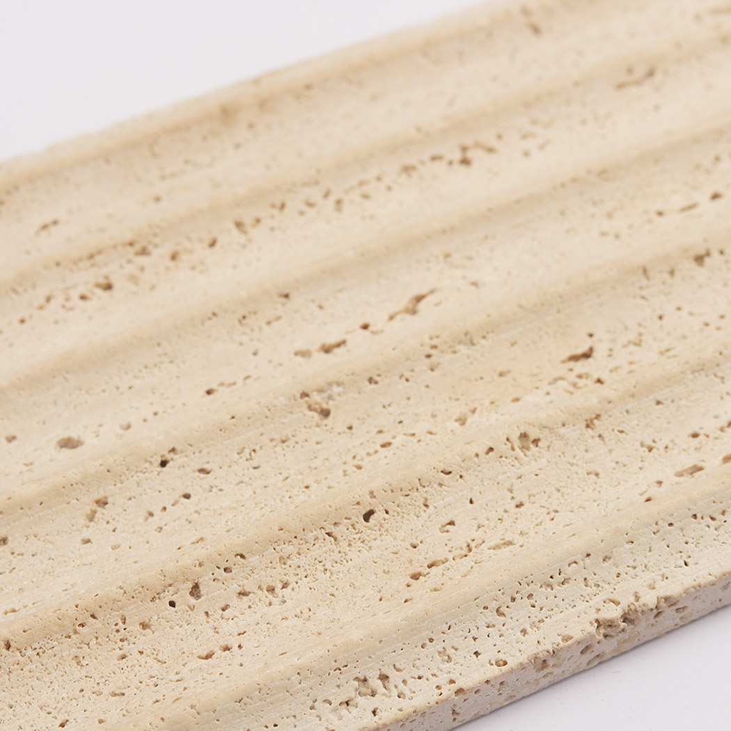 Close up of beige travertine fluted tile with soft porous stone texture