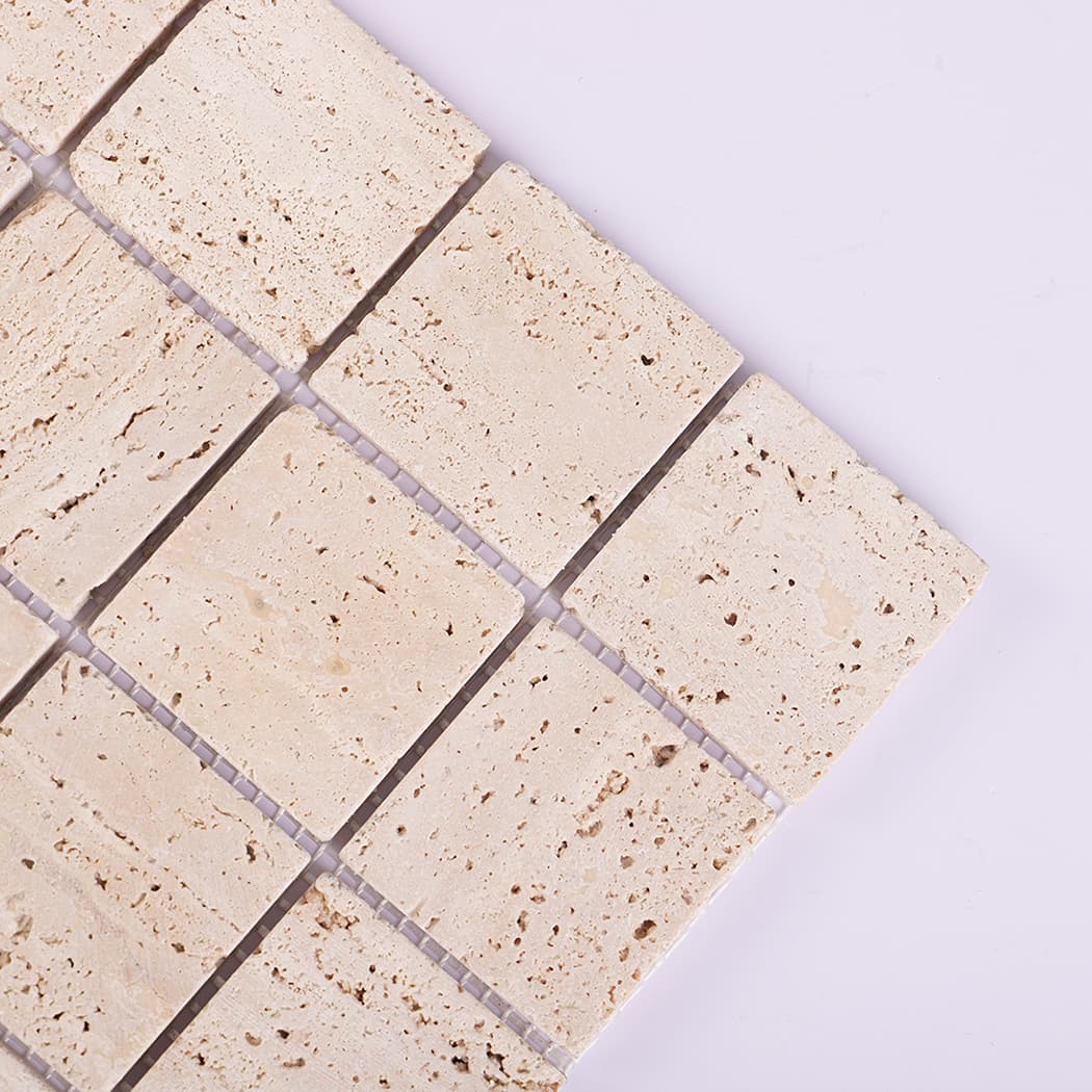 Close-up of beige travertine mosaic tile showing natural texture.