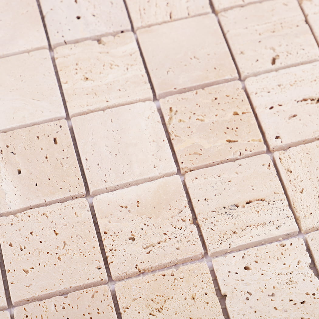 Detailed close-up showing porous surface of beige travertine tiles.