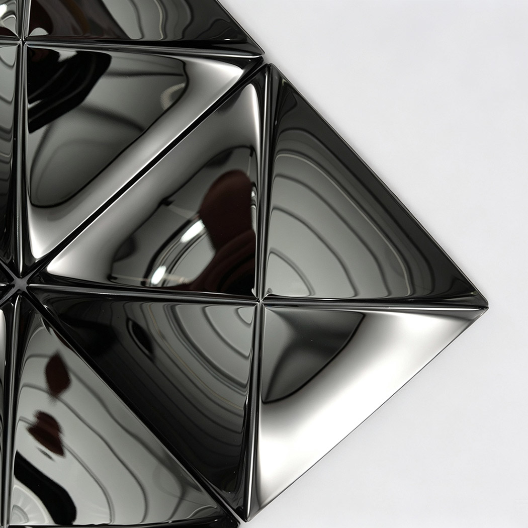Close-up of black 3D shaped wall tiles with a reflective metal surface