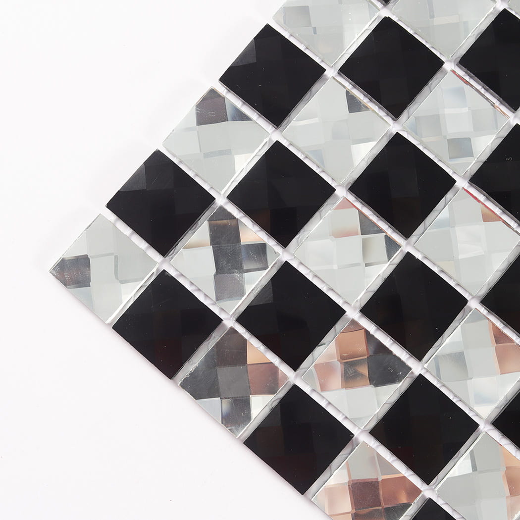 Close up angled view of a corner of black and silver faceted mirror mosaic tile sheet.
