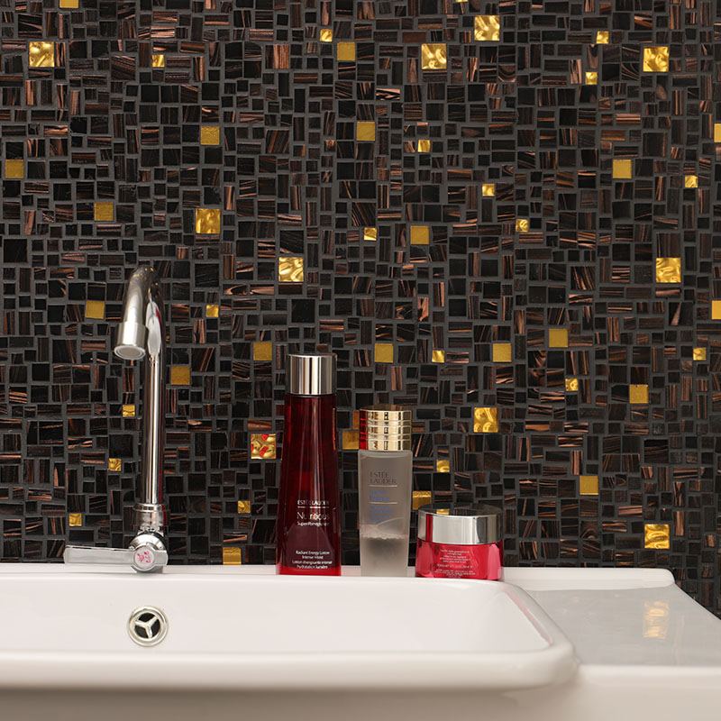 Black, copper, and gold mixed glass mosaic tile behind a bathroom sink