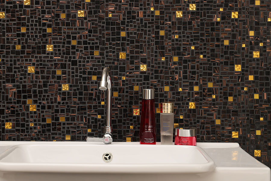 Black and copper mixed glass mosaic backsplash with gold accents in bathroom