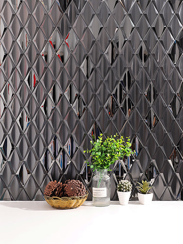 Close-up of black diamond 3D metal mosaic tile wall with potted plants and pinecones
