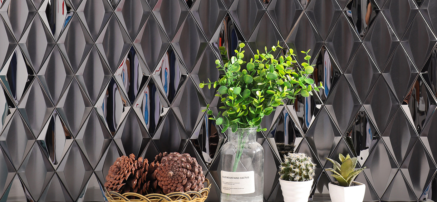 Close-up of black diamond 3D metal mosaic tile wall with potted plants and cacti
